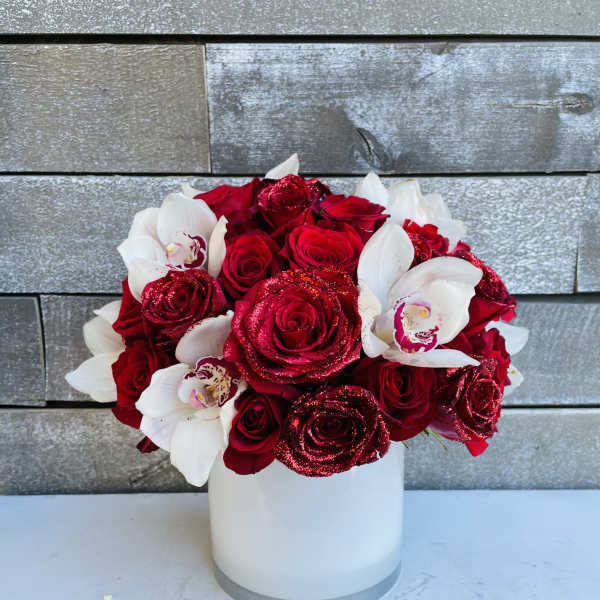 Red roses and white orchids arranged in a white vase