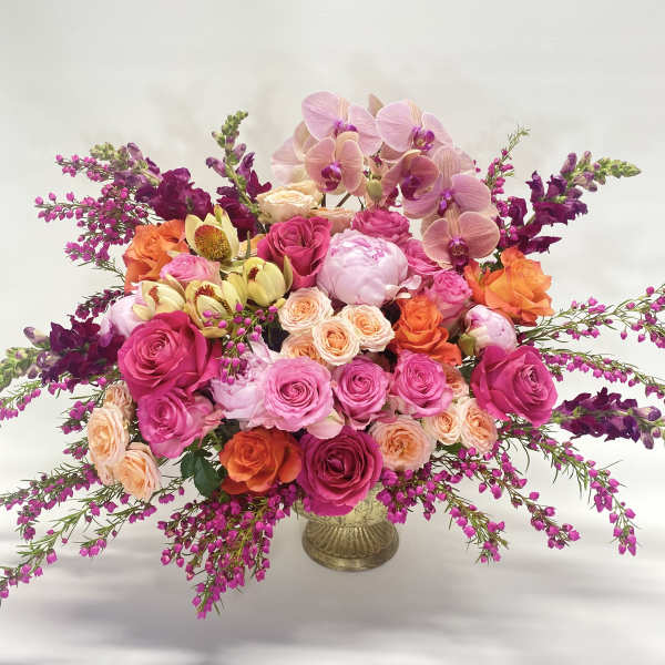 Large bouquet of pink, peach, and purple flowers in a gold vase