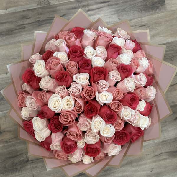 Large bouquet of pink, red, and white roses wrapped in pink paper