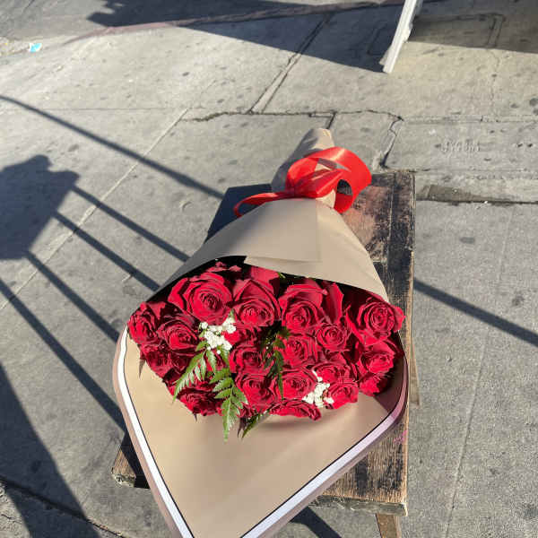 Bouquet of red roses wrapped in tan paper with a red ribbon