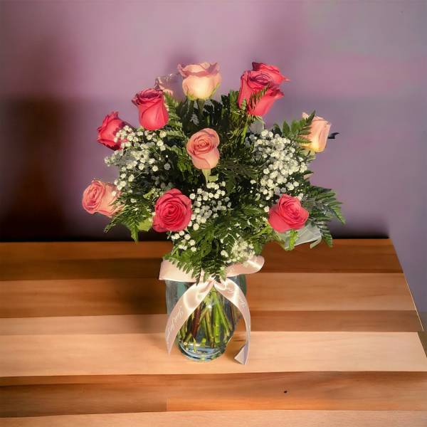 Bouquet of pink and peach roses in a glass vase with a ribbon