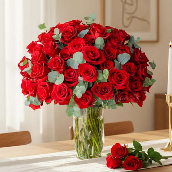 Red roses arranged in a clear glass vase with eucalyptus accents