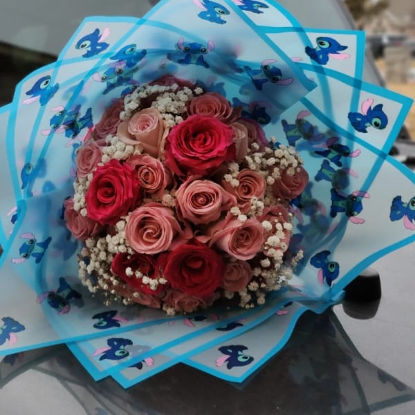 Bouquet of pink and red roses wrapped in blue Stitch-print paper
