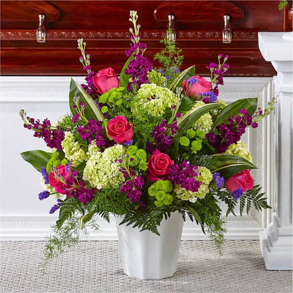Pink roses and purple flowers arranged in a white vase