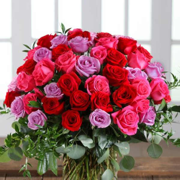 Bouquet of red, pink, and lavender roses in a glass vase