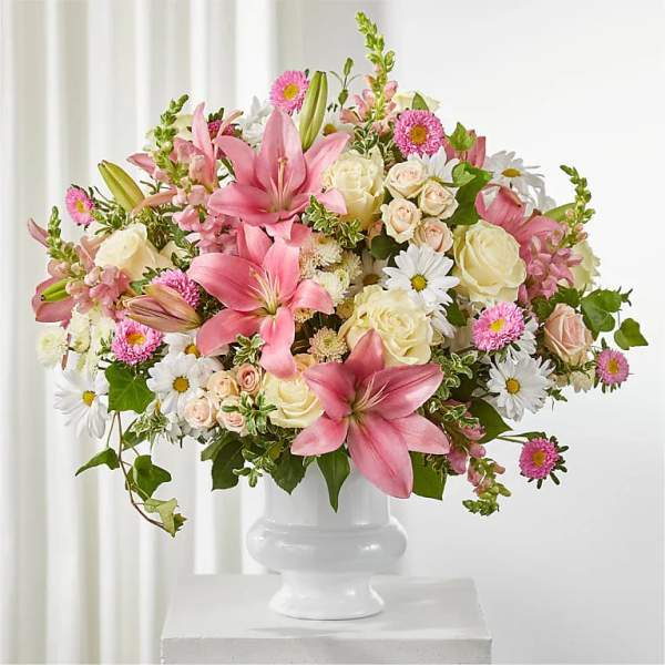 Pink lilies and cream roses in a white pedestal vase