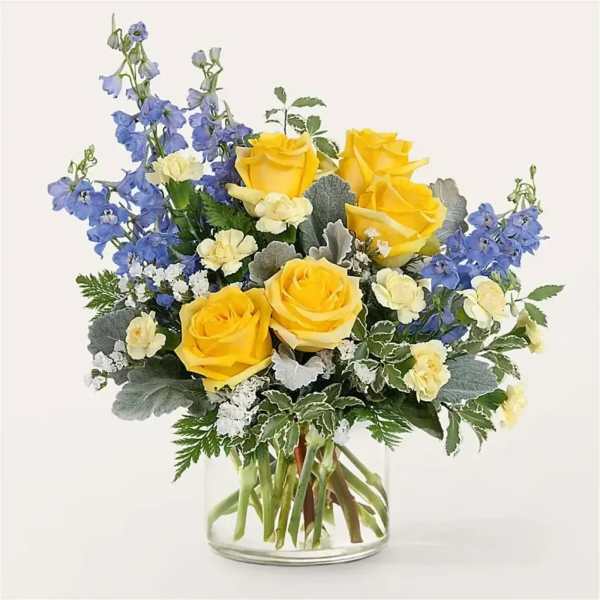 Yellow roses and blue delphinium in a clear glass vase