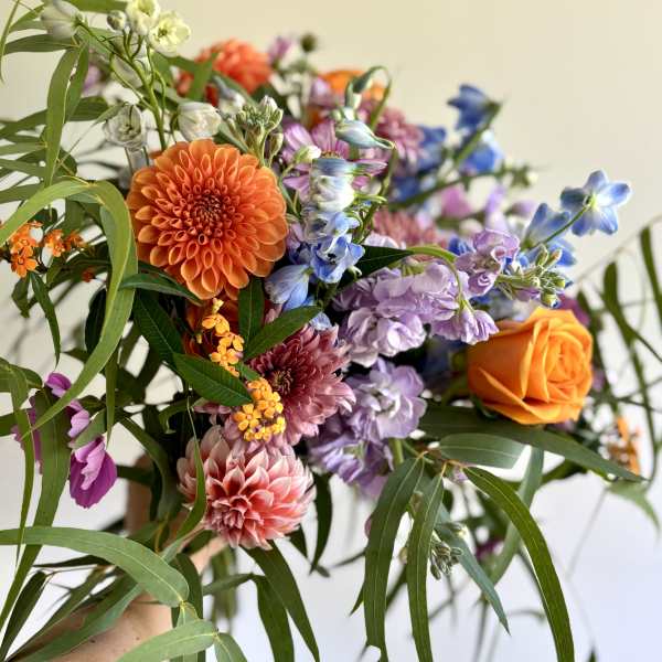 Handheld bouquet with orange, purple, pink, and blue flowers