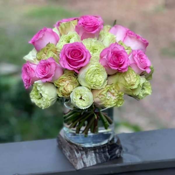 Pink and pale green roses arranged in a glass vase