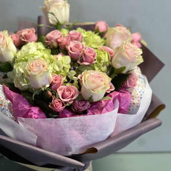 Bouquet of pink roses and green hydrangeas wrapped in pastel paper