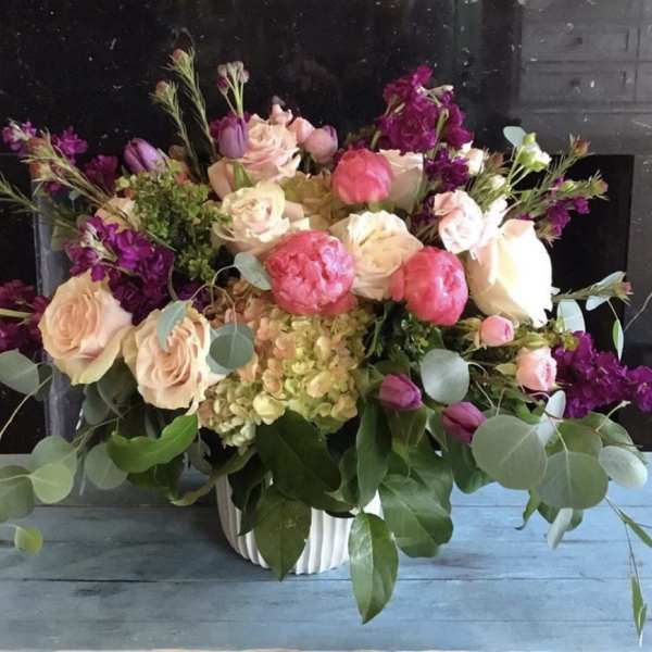 Mixed bouquet of pink and cream flowers in a white vase