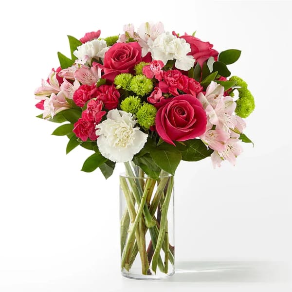 Bouquet of pink roses, carnations, and white flowers in a clear glass vase