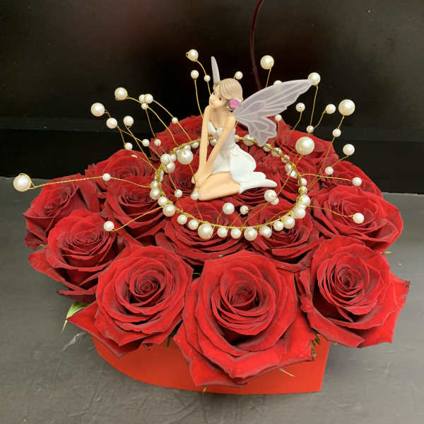 Red rose arrangement with a fairy figurine and pearl accents in a red box