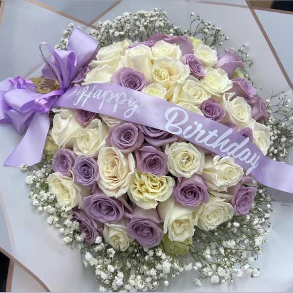 Bouquet of cream and lavender roses with a birthday ribbon