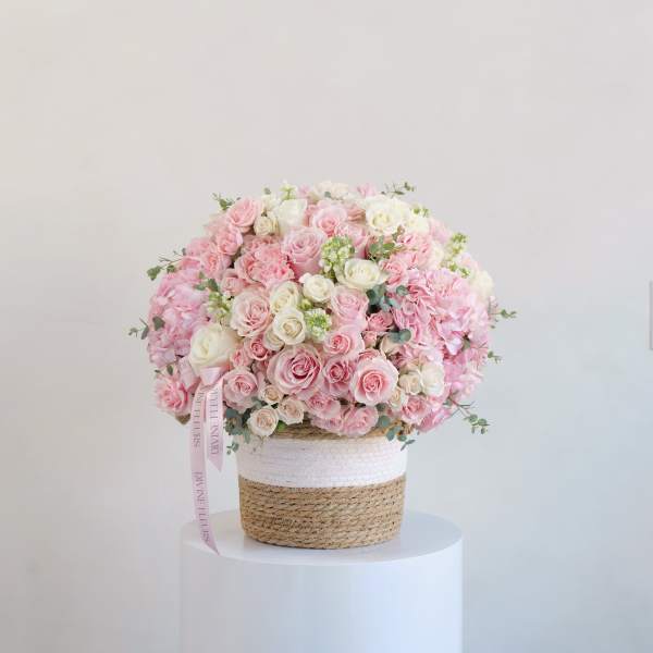 Large pink and white rose arrangement in a woven basket