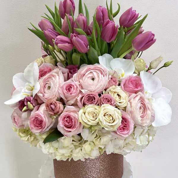 Pink tulips and roses arranged in a glittery rose-gold box