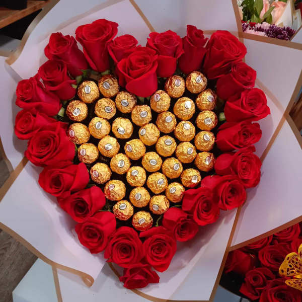 Heart-shaped bouquet of red roses with gold-wrapped chocolates in the center