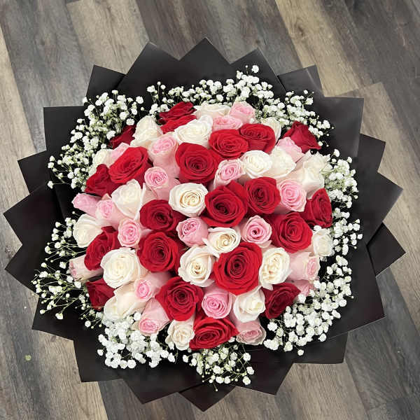 Bouquet of red, pink, and white roses with baby's breath in black wrap