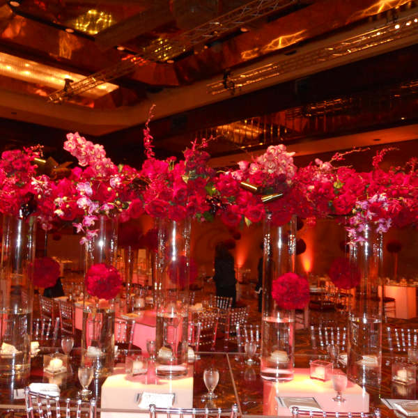 Tall pink floral centerpieces in clear glass vases at a banquet table