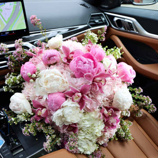 Pink and white bouquet of peonies and orchids on a car seat