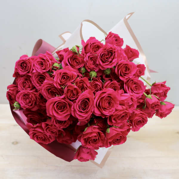 Large bouquet of bright pink roses wrapped in white and pink paper