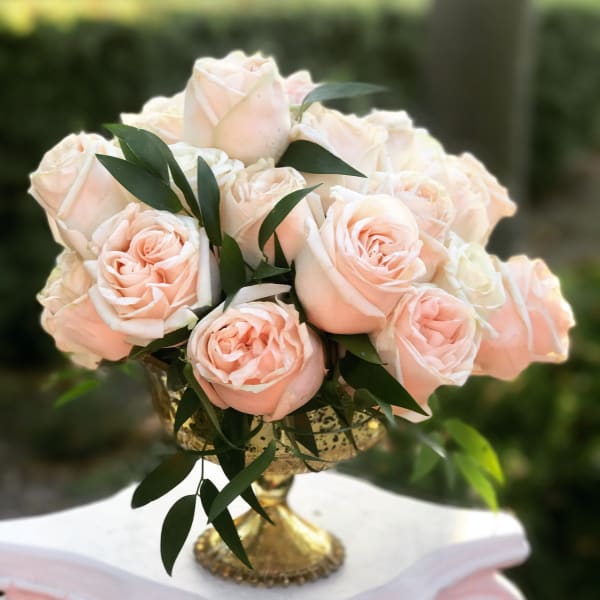 Blush roses arranged in a gold pedestal vase