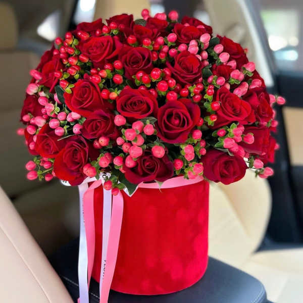 Red roses and pink berries in a red hatbox with ribbon