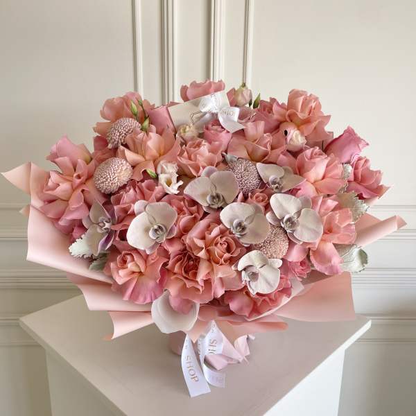 Large pink bouquet with roses and orchids wrapped in pastel paper