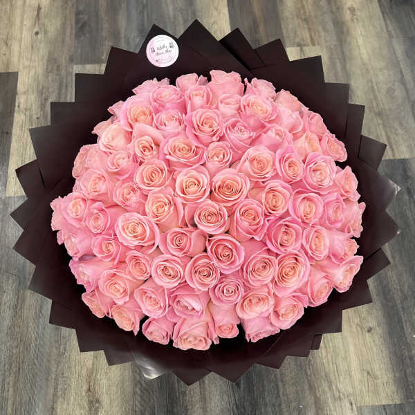 Large bouquet of pink roses wrapped in dark paper