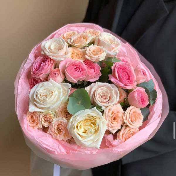 Bouquet of pink, peach, and white roses wrapped in pink paper