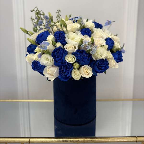 Blue and white rose bouquet in a dark cylindrical box