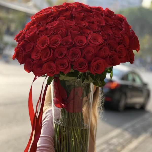 Large bouquet of red roses in a clear vase with red ribbon