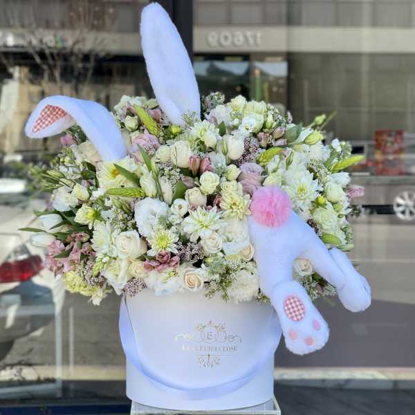 Large pastel flower arrangement with plush bunny ears and paws in a white box