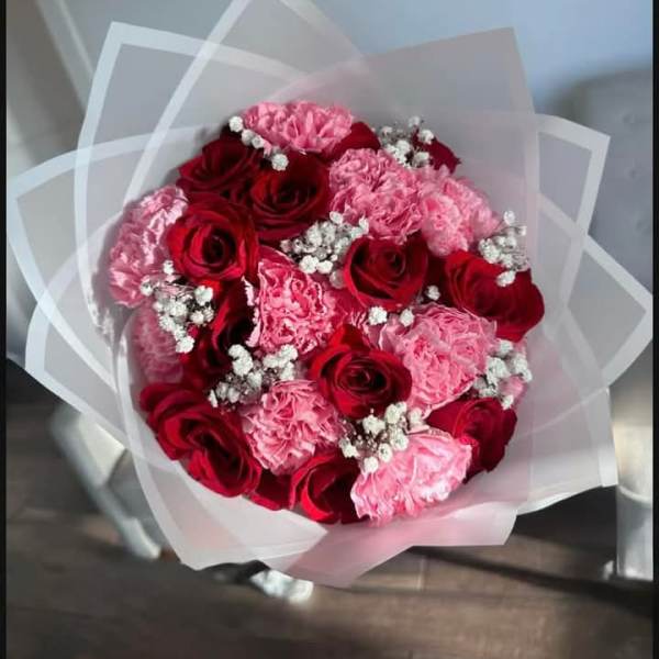 Bouquet of red roses and pink carnations wrapped in white paper