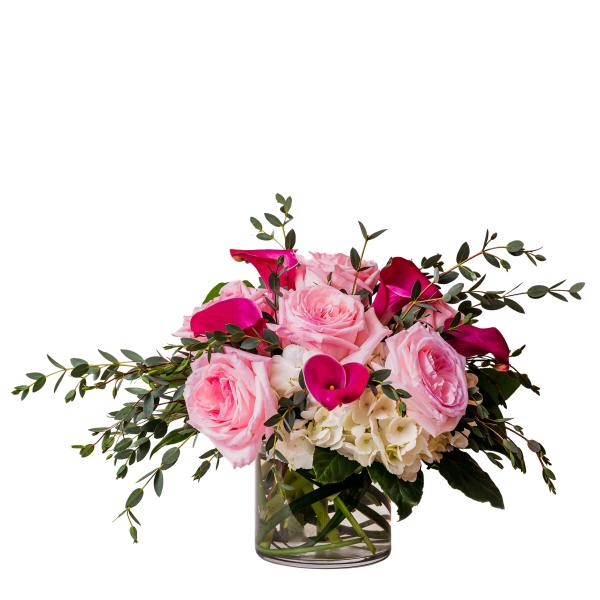 Pink roses and calla lilies in a glass vase with greenery
