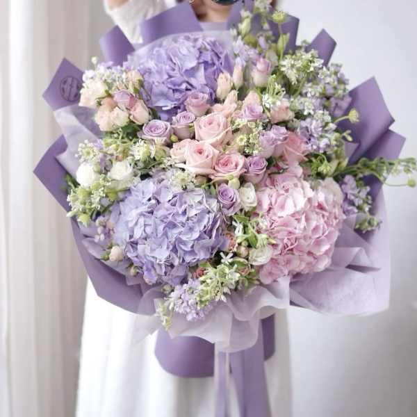 Lavender and pink bouquet with roses and hydrangeas wrapped in purple paper