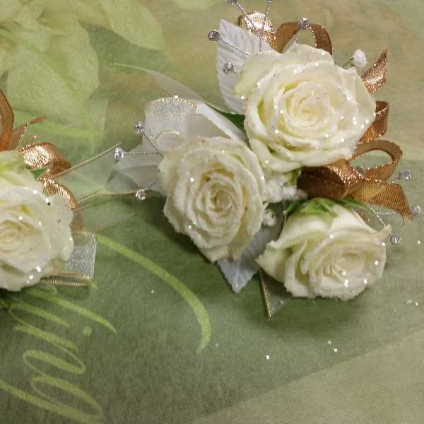 Two small white rose corsages with gold and silver ribbon accents