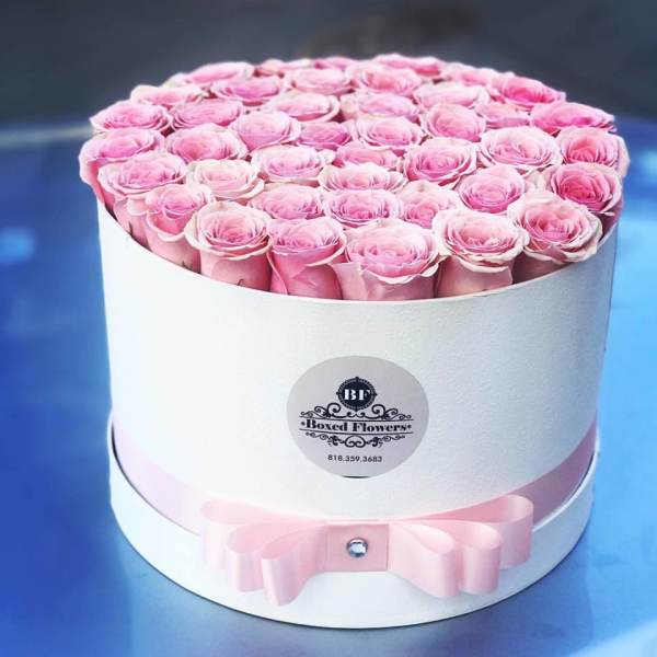 Round box filled with pink roses and a pink ribbon bow