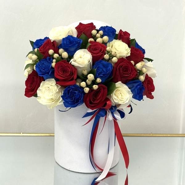 Red, white, and blue roses arranged in a white hat box with ribbon