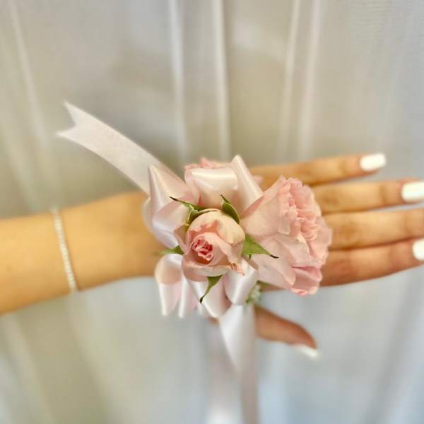 Pink floral wrist corsage with satin ribbon on a hand
