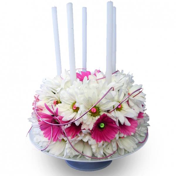 White and pink daisy arrangement with tall white candles