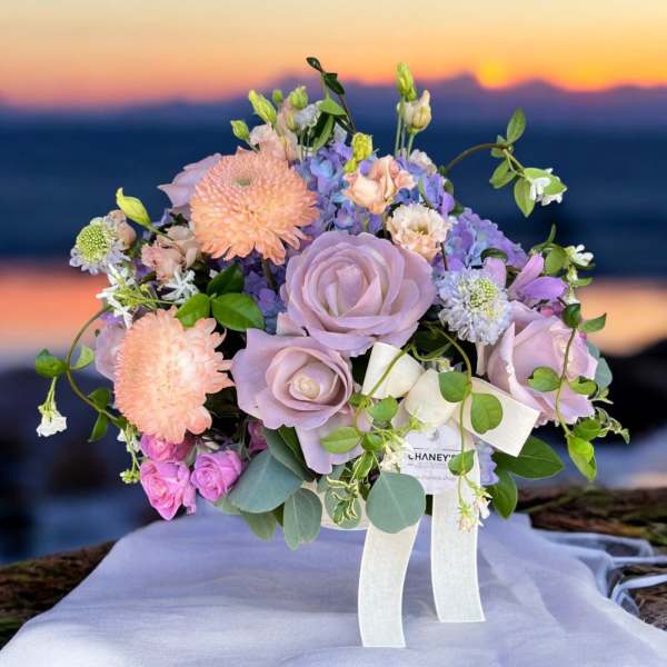 Lavender and peach bouquet with roses and dahlias tied with a white ribbon
