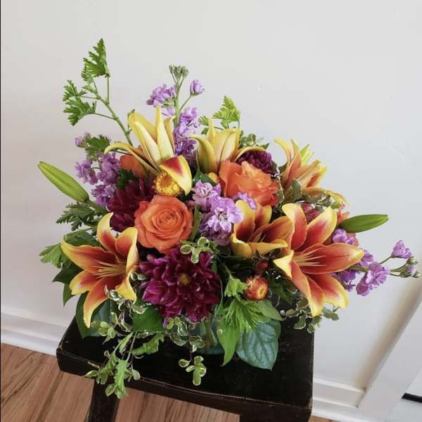 Bouquet of orange roses, lilies, and purple flowers