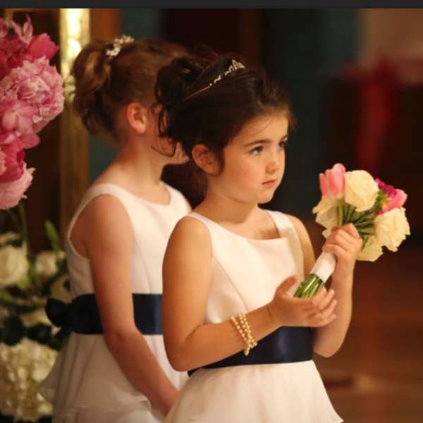 Two girls in white dresses holding small flower bouquets