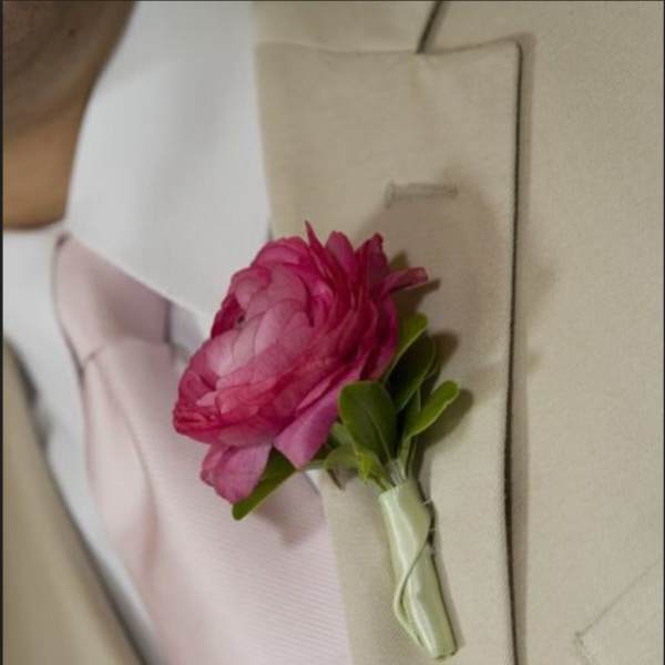 Pink boutonniere pinned to a beige suit jacket