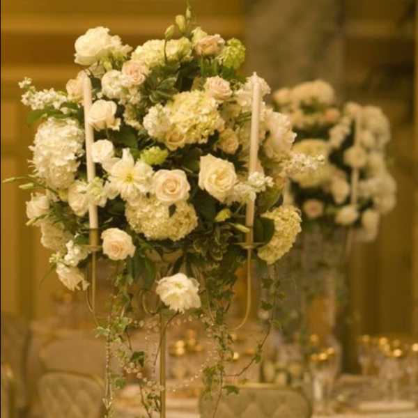 Tall white floral centerpiece on a gold-decorated banquet table