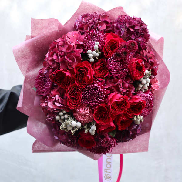 Bouquet of red and magenta flowers wrapped in pink paper