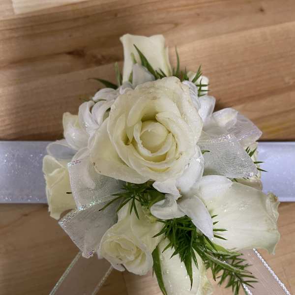 White rose corsage with ribbon and greenery