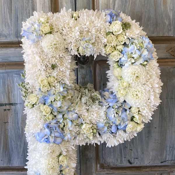 Large floral letter P made of white and pale blue flowers