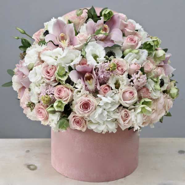 Low pink and white flower arrangement with orchids and roses in a round pink hat box